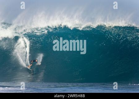 Ein junger Mann, der eine große Welle in Pipeline am Nordufer von Oahu, Hawaii, surft Stockfoto