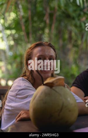 Eine Frau trinkt eine frische Kokosnuss auf einer tropischen Insel. Stockfoto