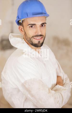 Der junge Ingenieur trägt einen gelben Helm mit gekreuztem Arm Stockfoto