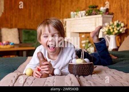 Nettes Schulkind, Junge, Korb mit ostereiern auf osterhintergrund, Studioaufnahme Stockfoto