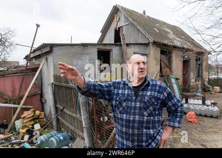 MYKOLAIV Reg, UKRAINE - 2. März 2024: Ein älterer Mann, ein ortsansässiger Bewohner, wird vor seinem beschädigten Haus gesehen und erzählt, was in seinem Dorf in der Region Mykolaiv passiert ist Stockfoto