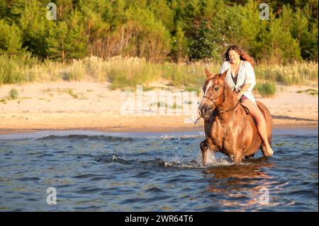 Eine Frau zu Pferd, die einen See überquert Stockfoto