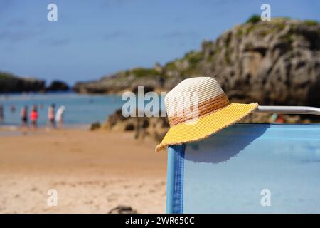 Eine Strandszene mit einem gelben Hut auf einer Liege. Sommerferien an der Küste Stockfoto