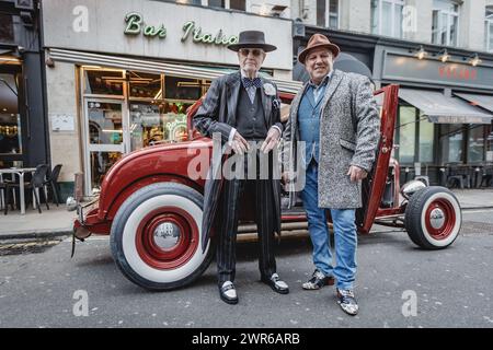 Zwei gut gekleidete Herren stehen neben einem Oldtimer vor der Bar Italia im Londoner Soho. Stockfoto