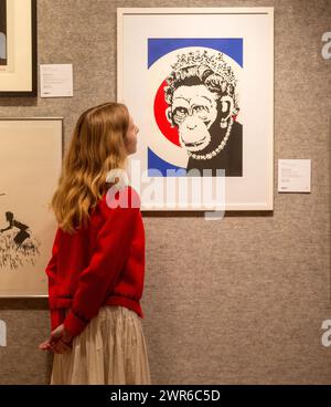 London, England, Großbritannien. März 2024. Mitarbeiter posiert mit Monkey Queen von Banksy (Foto: © Tayfun Salci/ZUMA Press Wire) NUR FÜR REDAKTIONELLE ZWECKE! Nicht für kommerzielle ZWECKE! Quelle: ZUMA Press, Inc./Alamy Live News Stockfoto