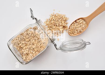 Haferflocken im Glasgefäß mit Löffel Haferflocken auf weißem Hintergrund. Draufsicht. Gesunde Speisen zum Frühstück Stockfoto