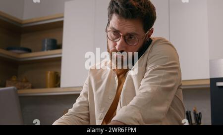 Kaukasischer Multitasking-Mann mit Laptop, der von zu Hause aus arbeitet, telefoniert Handy-Business Freelancer Geschäftsmann in Quarantäne. Männlicher Kunde bestellt Essen Stockfoto