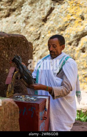 Lalibela, Äthiopien - 1. Mai 2019: Man zählt gesammelte Gelder von Gläubigen außerhalb der St. George Church, Lalibela, wirft Licht auf die Finanzhilfe Stockfoto