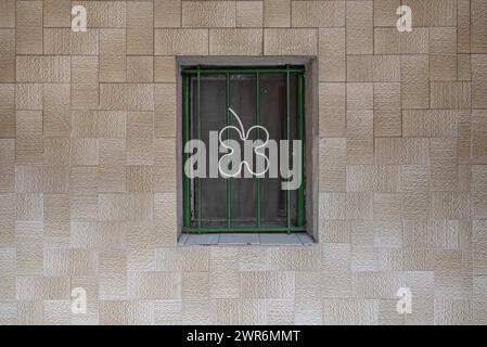 Ein kleines Fenster mit Metallstangen an der gefliesten Wand Stockfoto