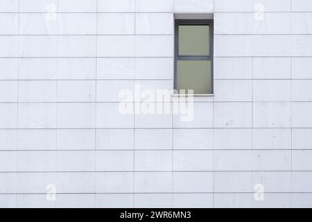Kleines rechteckiges Fenster aus grauem Aluminium an einer weiß gekachelten Wand Stockfoto