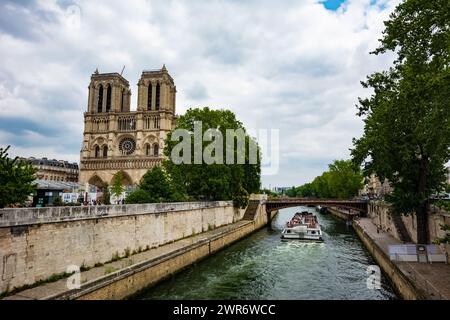 Paris, Frankreich - 23. Juli 2022: Notre-Dame mit Kanal daneben und Touristenboot. Stockfoto