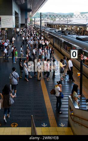 Passagiere, die in der Warteschlange für ihren Zug stehen, Bahnhof Kyoto, Japan. Stockfoto