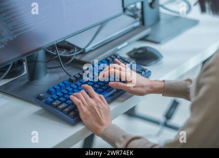 Nahaufnahme eines asiatischen Promt-Ingenieurs entwickelt eine Codierungs-App mit Softwaredaten, die vor dem Computermonitor im Büro sitzen Stockfoto