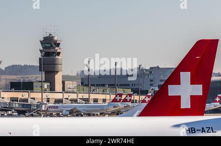 Zürich, Schweiz - 28. Februar 2022: Blick auf das Terminal A mit dem Kontrollturm des Flughafens Zürich. Eine Heckflosse eines Embraer Flugzeug der SC Stockfoto