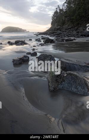 Ein felsiger Strand mit einer felsigen Küste und einem Gewässer im Hintergrund. Der Strand ist größtenteils mit Felsen bedeckt, mit etwas Sand verstreut. Die Stockfoto