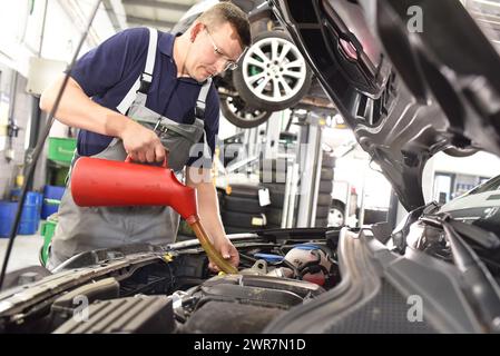 Motoröl vom Auto durch einen Mechaniker in der Autowerkstatt Stockfoto