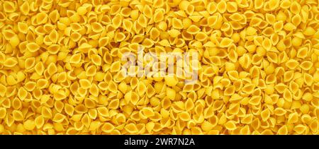 Italienische Pasta Conchiglie Hintergrund. Bio-Vollkornnudeln. Direkt darüber, Nahaufnahme, Überkopf. Stockfoto