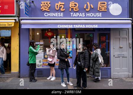 Gäste, die ihre Snacks und Speisen am 6. März 2024 in London, Großbritannien, vor dem Chinese Tapas House in Chinatown genießen. Chinatown ist eine ethnische Enklave an der Grenze zu Soho und befindet sich derzeit in der Gerrard Street. Es enthält eine Reihe chinesischer Restaurants, Bäckereien, Supermärkte, Souvenirläden und anderer chinesischer Unternehmen. Stockfoto