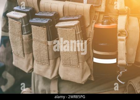 Armeeweste mit einem Walkie-Talkie-Kragen betäuben Granaten leuchtende Stäbe stehen auf einer Holzkiste mit Munition. Stockfoto