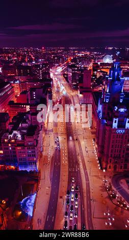 Vertikale Luftaufnahme einer belebten Stadtstraße bei Nacht mit leuchtender violetter Beleuchtung und Verkehrswegen in Liverpool, Großbritannien. Stockfoto