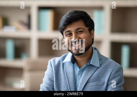 Ein erfolgreicher indischer Geschäftsmann lächelt selbstbewusst und repräsentiert Führungsqualitäten in modernen Büros Stockfoto