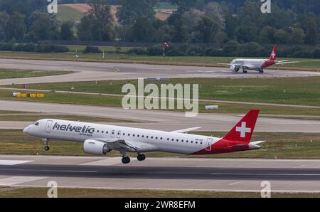 Vor einem heftigen Gewitterfront landet ein Embraer 190-E2 von Helvetic Airways auf dem Flughafen Zürich. Registrierung HB-AZI. Dahinter startete ein FL Stockfoto