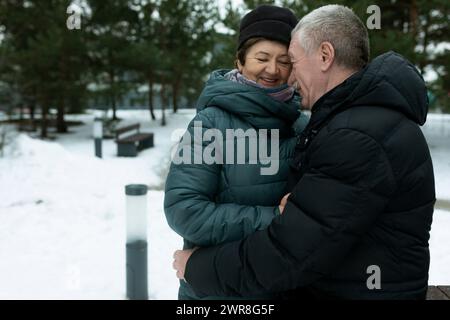Niedliches, reifes Paar, das im Winter beim Spaziergang im Park Liebe für einander erlebt Stockfoto