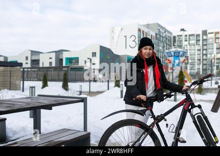 Europäische Frau in Winterkleidung, die im Winter Fahrrad fährt Stockfoto