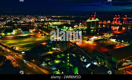 Nächtliche Luftaufnahme eines Industriehafens mit beleuchteten Kränen und Lagerhäusern, die den urbanen Handel in Liverpool, Großbritannien, zeigt. Stockfoto