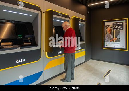 Ein älterer Mann sammelt Geld am Geldautomat der Bank-neutralen Bancontact-GELDSTELLE in Flandern, Belgien. MODELL FREIGEGEBEN Stockfoto