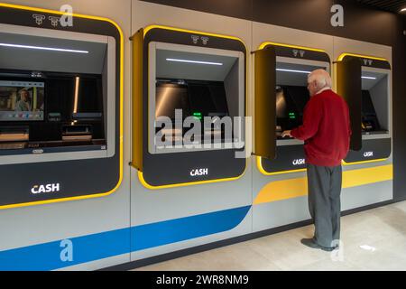 Ein älterer Mann sammelt Geld am Geldautomat der Bank-neutralen Bancontact-GELDSTELLE in Flandern, Belgien. MODELL FREIGEGEBEN Stockfoto