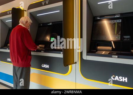 Ein älterer Mann sammelt Geld am Geldautomat der Bank-neutralen Bancontact-GELDSTELLE in Flandern, Belgien. MODELL FREIGEGEBEN Stockfoto