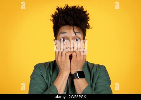 Nahaufnahme eines verängstigten afroamerikanischen Mannes, der auf Gelb grimmt Stockfoto