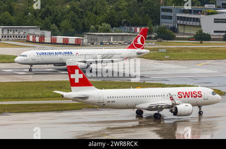 Ein Airbus A321-200 von Turkish Airlines startete von Piste 28 auf dem Flughafen Zürich. Registrierung TC-JSC. Davor wartet ein Airbus A220-100 von Swis Stockfoto
