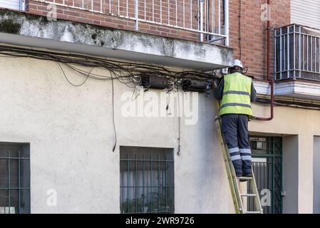 Ein Mitarbeiter der Telefongesellschaft, der auf einer Leiter arbeitet Stockfoto