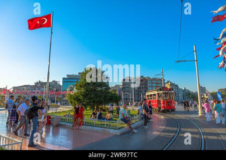 Istanbul, Türkei - Aug 2,2023: Pulsierendes urbanes Leben auf dem taksim-Platz mit der berühmten roten Straßenbahn und der türkischen Flagge Stockfoto