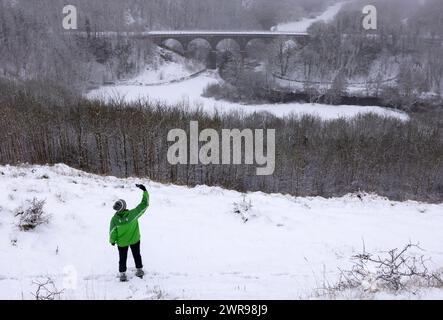 12/2023 Ein Wanderer trotzt den winterlichen Bedingungen, nachdem er über Nacht in Monsal Head, nahe Bakewell, im Derbyshire Peak District, stark schneebedeckt ist. Alle Stockfoto