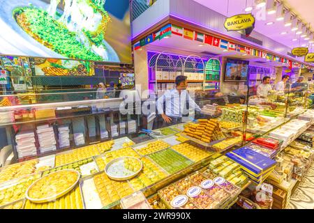 Istanbul, Türkei - Aug 2,2023: Bunte Ausstellung verschiedener Baklava in einem geschäftigen türkischen Dessertgeschäft mit Mitarbeitern, die Kunden bedienen. Traditionell Stockfoto