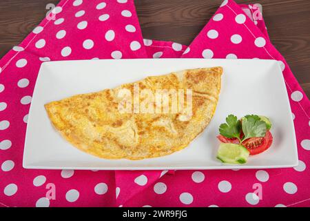 Omelette mit Gemüsesalat. Nahaufnahme eines Tellers mit einer typischen Tortilla de Patatas, spanischem Omelett, auf einem gedeckten Tisch. Stockfoto