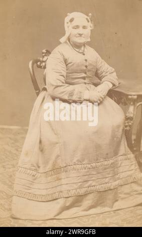 Porträt einer Frau mit traditionellem Hut, die an einem Tisch sitzt, dieses Foto ist Teil eines Albums. Hermanus Jodocus Weesing, Amsterdam, 1868 - 1900, fotografische Unterstützung, Albumendruck, Höhe 85 mm x Breite 53 mm, Foto Stockfoto