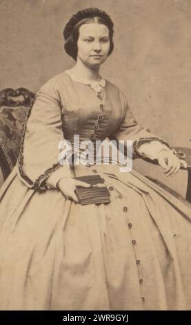 Porträt einer sitzenden jungen Frau mit Buch in der Hand, dieses Foto ist Teil eines Albums., Willem Tinker, 1860 - 1880, fotografische Unterstützung, Albumenabdruck, Höhe 100 mm x Breite 57 mm, Foto Stockfoto