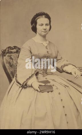 Porträt einer sitzenden jungen Frau mit Buch in der Hand, dieses Foto ist Teil eines Albums., Willem Tinker, 1860 - 1880, fotografische Unterstützung, Albumenabdruck, Höhe 104 mm x Breite 59 mm, Foto Stockfoto