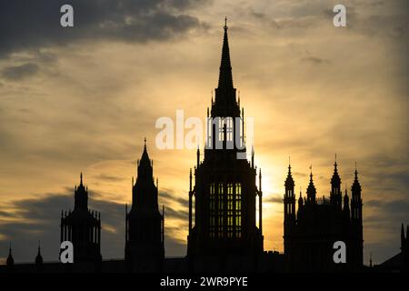 Die Silhouette des zentralen Turms der Parlamentsgebäude ist vor der untergehenden Sonne sichtbar. Houses of Parliament, London, Großbritannien. März 2024 Stockfoto