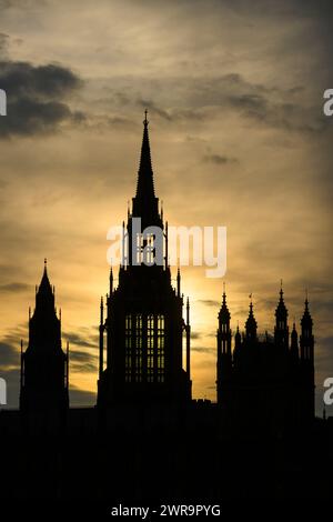 Die Silhouette des zentralen Turms der Parlamentsgebäude ist vor der untergehenden Sonne sichtbar. Houses of Parliament, London, Großbritannien. März 2024 Stockfoto