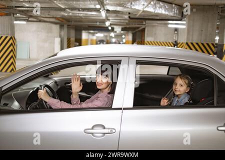 Mutter und kleines Vorschulmädchen sitzen in einem modernen Auto mit geöffneten Fenstern. Stockfoto