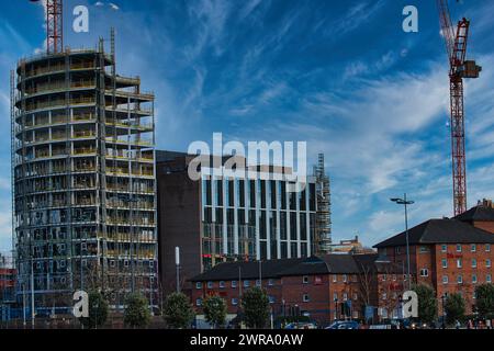 Städtische Baustelle mit Kränen und sich entwickelndes Hochhaus vor blauem Himmel mit Wolken in Liverpool, Großbritannien. Stockfoto