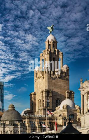 Historisches Gebäude mit einer Statue auf der Spitze unter blauem Himmel mit Wolken in Liverpool, Großbritannien. Stockfoto