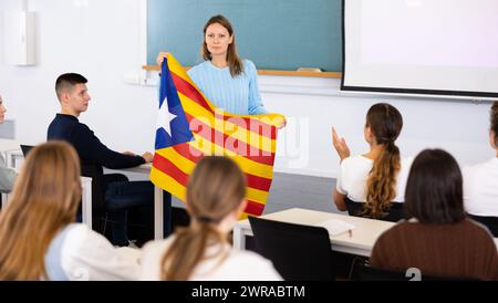 Geografie-Unterricht in der Schule - der Lehrer spricht über Katalonien und hält die Flagge in seinen Händen Stockfoto