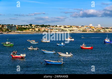 Wunderschöner Blick auf kleine Fischerboote an sonnigem Tag in der Bucht von Cascais, Portugal, ruhige und luxuriöse Küstenstadt in der Nähe von Lissabon mit Stränden und kleinem Hafen. Klarer blauer Himmel, Wolken, Sonnenschein, ruhiges Meer, Häuser an der Küste. Stockfoto