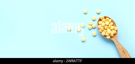 Holzlöffel mit gelben Pillen auf blauem Hintergrund mit Platz für Text Stockfoto